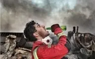 عکس حاشیه‌ساز از یک ‌آتش‌نشان در حمله به تهران | واکنش جالب یک آتش نشان به آگهی تبلیغاتی