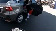 آویزان شدن یک بچه از درب ماشین در حال حرکت!+ویدئو